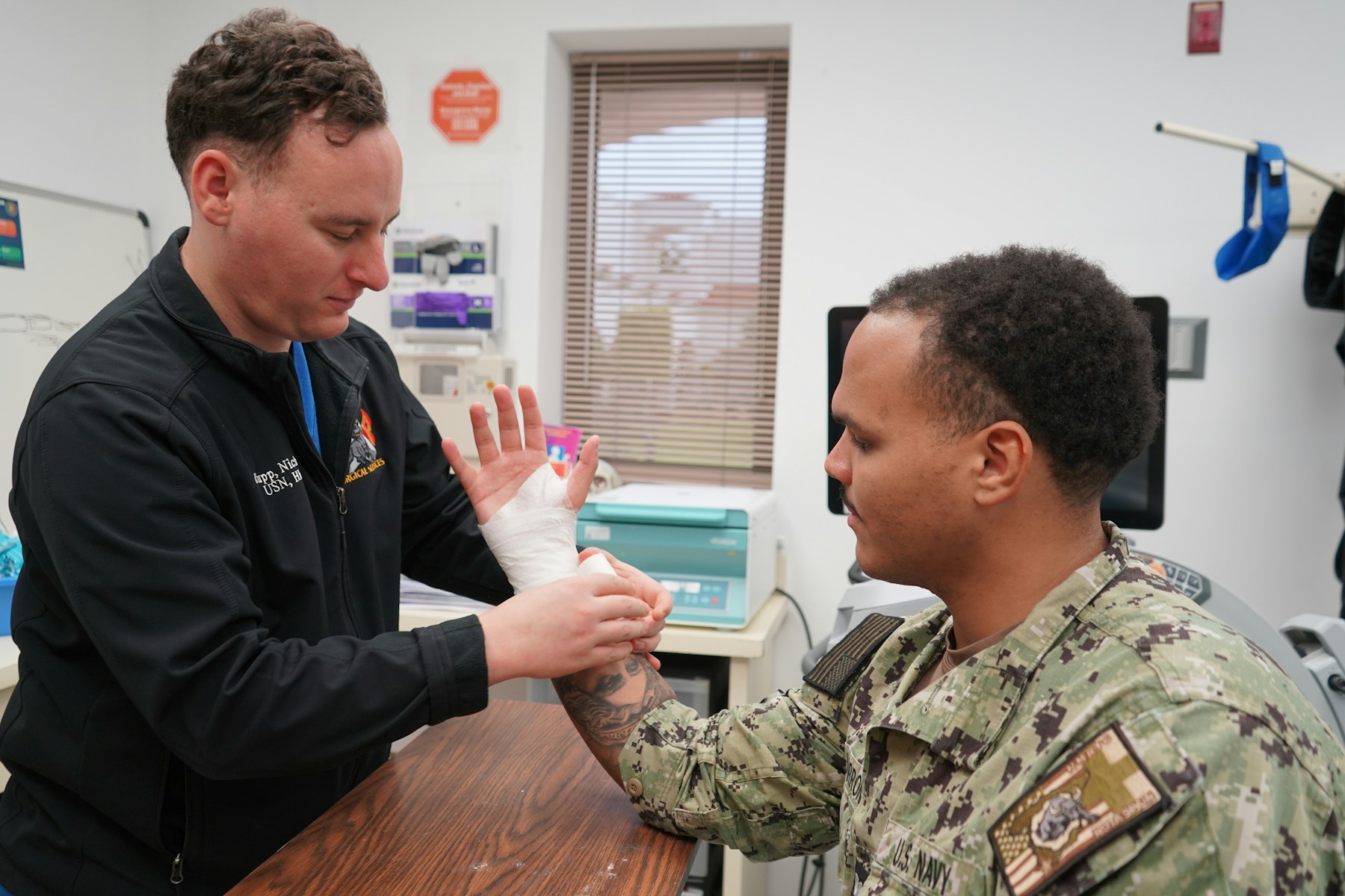 A clinical professional wrapping a patient’s hand with a clean dressing