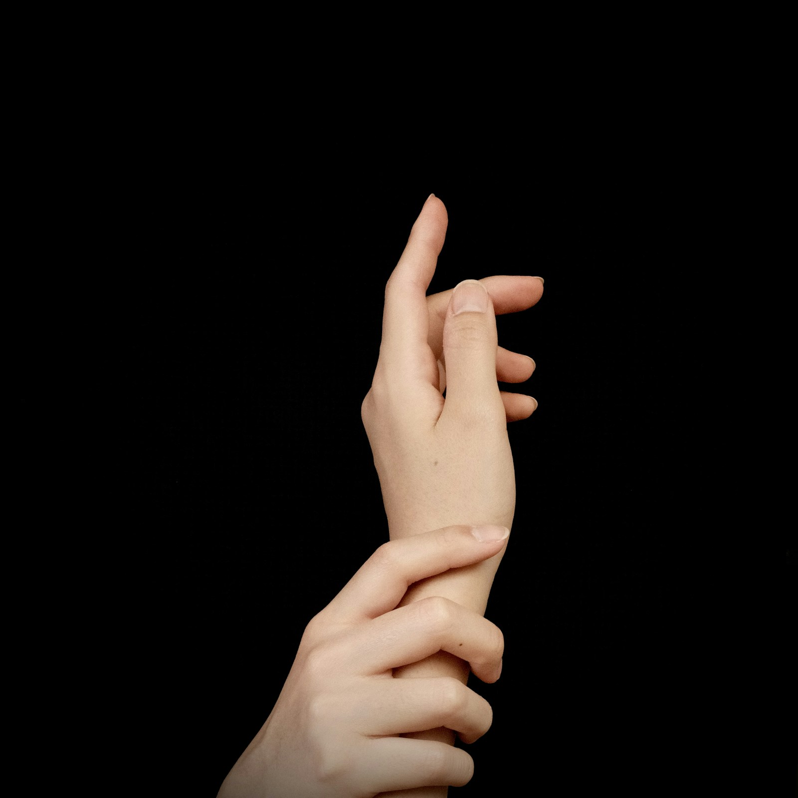 Close-up of naturally positioned fingers with the other hand gently supporting the wrist