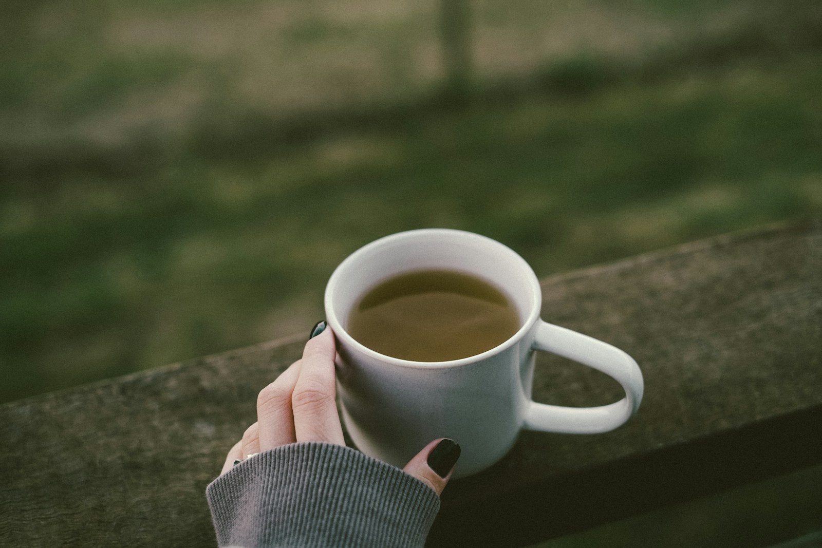 A hand holding a ceramic cup outdoors, illustrating everyday grip