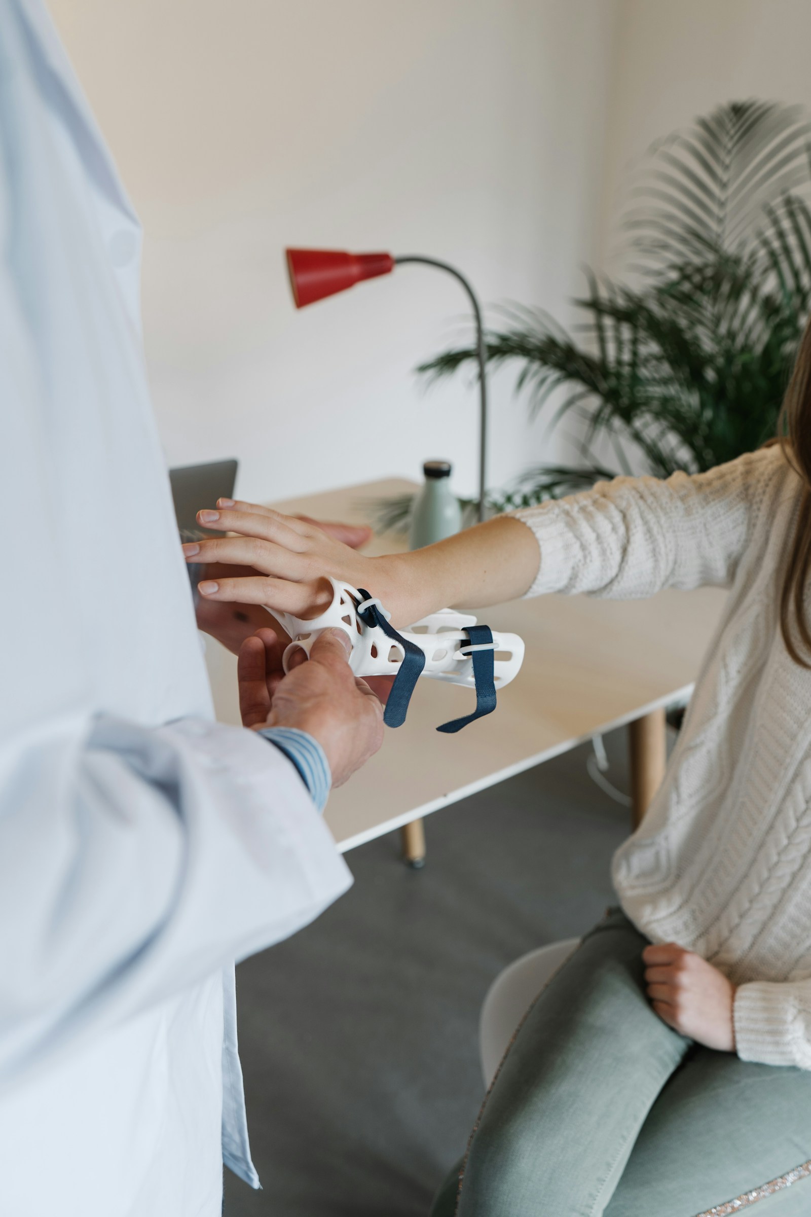 Clinician fitting a custom white wrist support around a patient’s hand and forearm